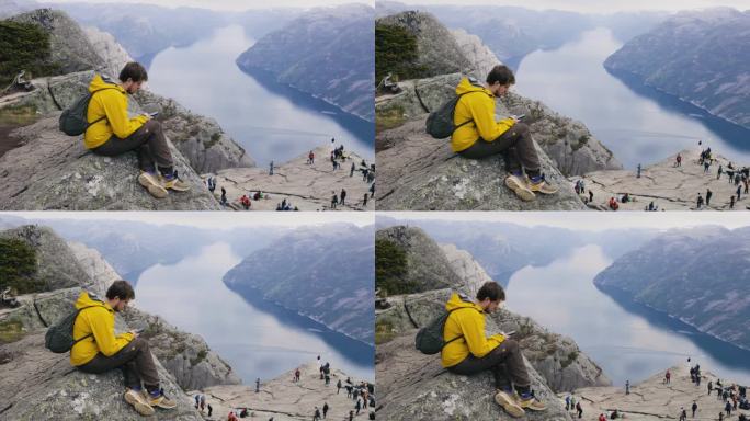 在挪威布道石山顶上使用智能手机的男子侧视图