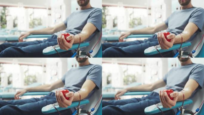 男性献血者的手的特写镜头。白人男子挤压心形红球，将血液通过管道泵入袋中。捐赠给心脏手术患者。