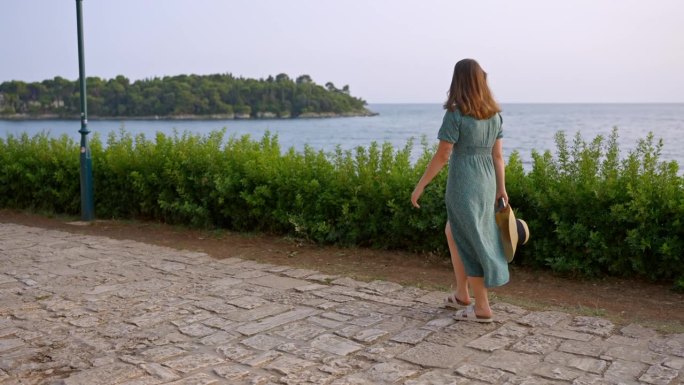 身穿背心裙的年轻女子在罗维尼海边散步