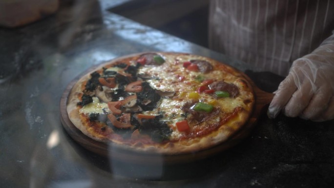 意大利厨师在披萨店准备用轮刀切两个披萨。