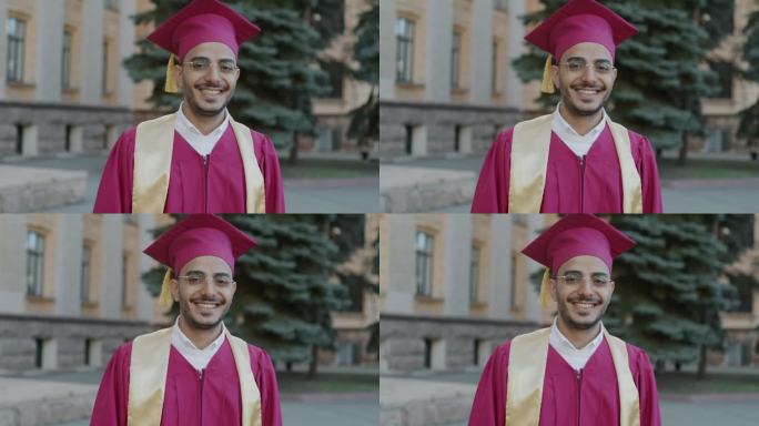 慢动作肖像的阿拉伯男子毕业生站在校园里穿着长袍和砂浆板微笑