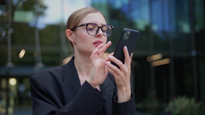 忧心忡忡的戴眼镜的年轻女商人不明白为什么她的智能手机上没有蜂窝网络连接或Wifi网络信号，她把手机举