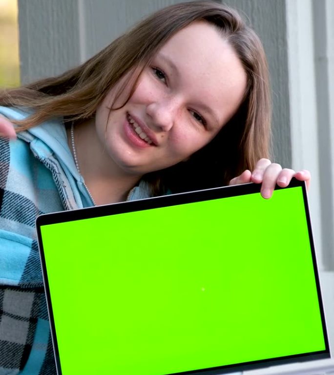 十几岁的女孩展示笔记本电脑用空模型绿色度键屏，It专家，技师维修服务，技术支持维修教育学校广告娱乐网