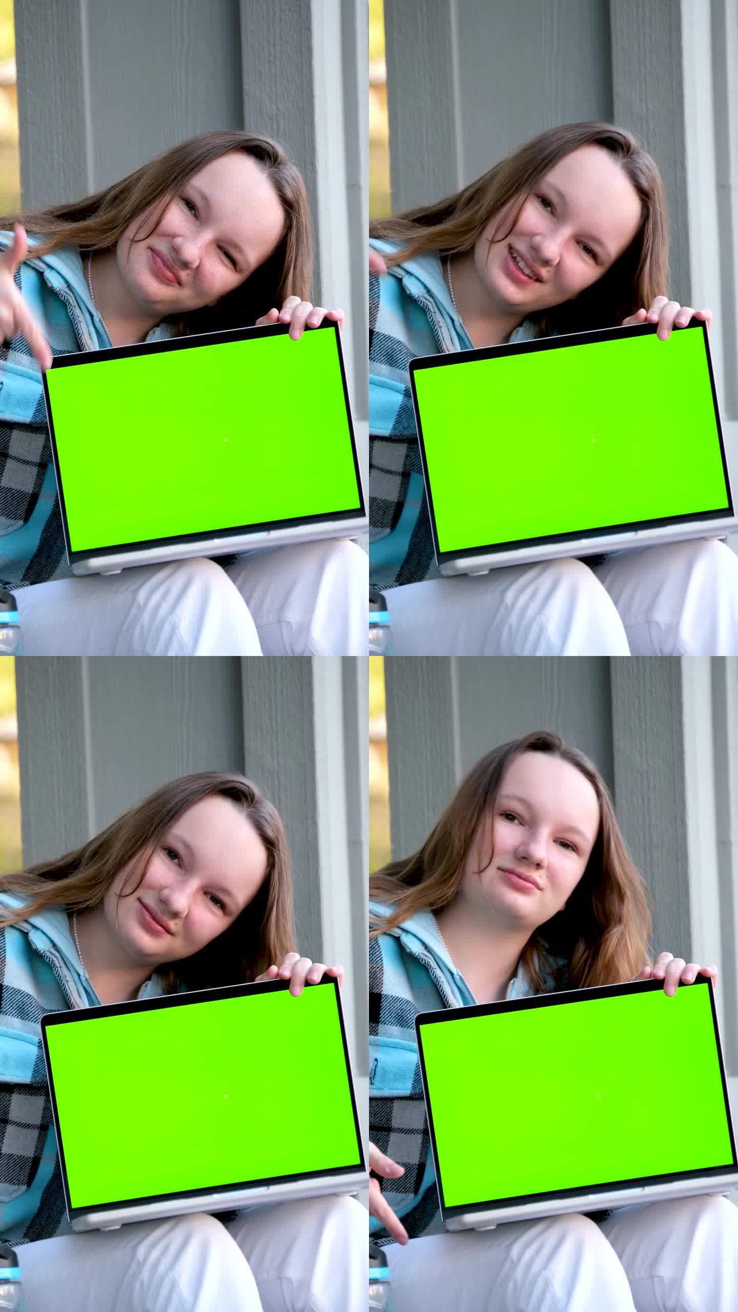 十几岁的女孩展示笔记本电脑用空模型绿色度键屏，It专家，技师维修服务，技术支持维修教育学校广告娱乐网