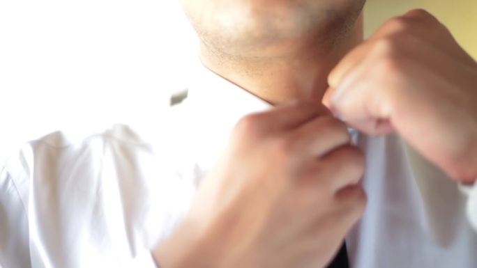 一个商人调整领带的特写镜头，一个人在办公室放松领带。男人忙了一天整理领带，累了。