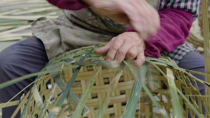 乡村老人在院子里用竹条编竹篮