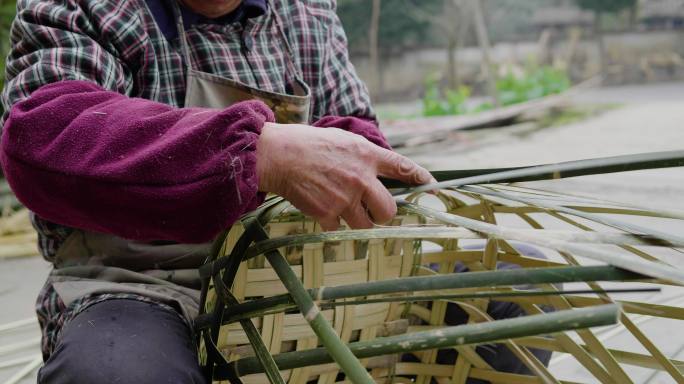 乡村老人在院子里用竹条编竹篮