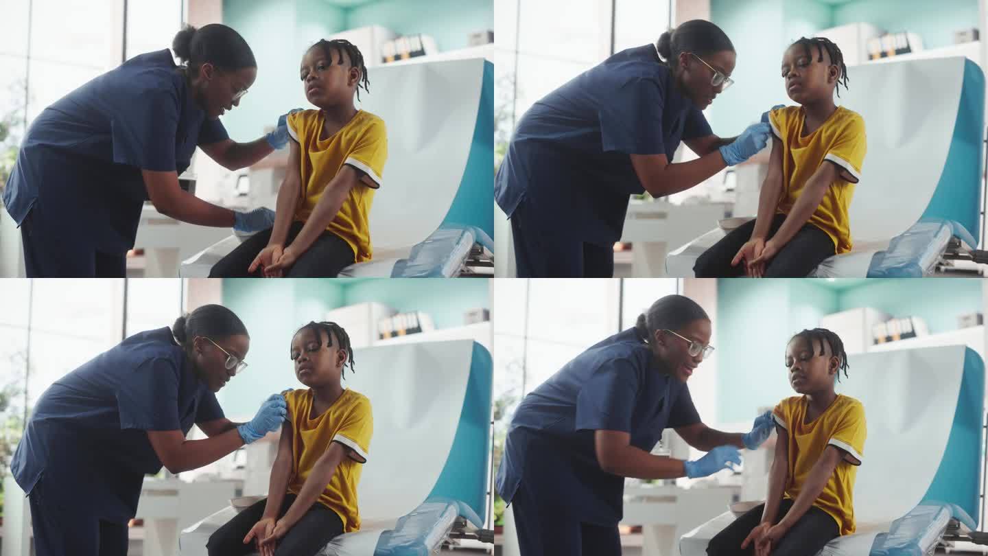 一个非洲裔美国男孩坐在光明医院的椅子上。黑人女护士在小儿麻痹症疫苗注射后给孩子贴片。职业女性和年轻男