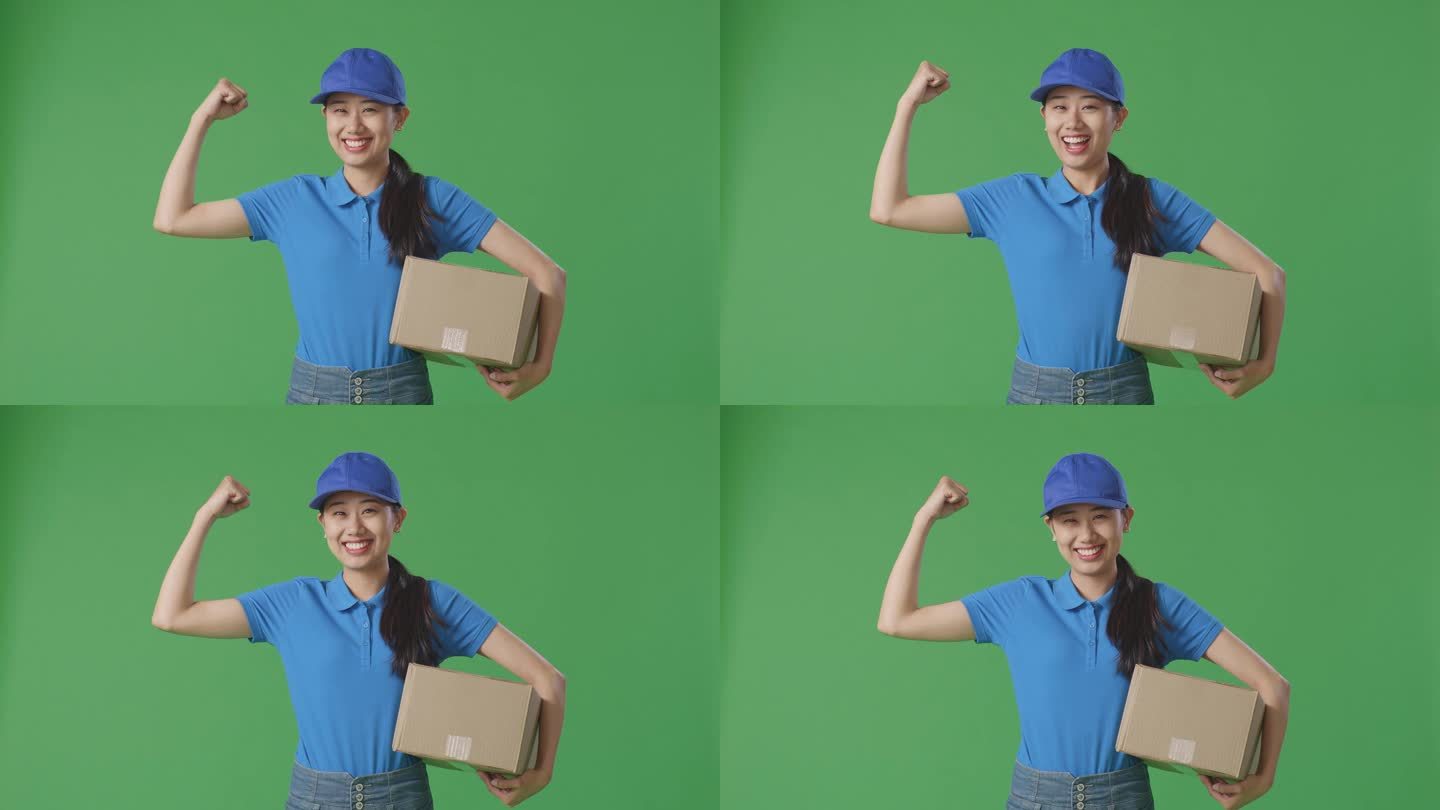 亚洲女快递员穿着蓝色制服，微笑着，肌肉发达，在工作室绿屏背景下送纸箱