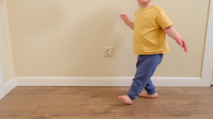 蹒跚学步的婴儿用手伸进家里墙上的电源插座。儿童手指触电的危险和保护。2岁左右(1岁11个月)
