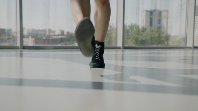运动员在健身房做有氧运动时，穿着运动鞋的男腿跳跳绳的特写