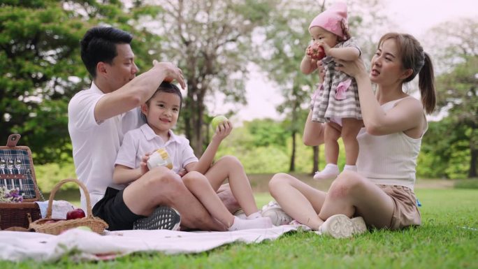 亚洲家庭坐在公园里休息，一起快乐地玩耍。