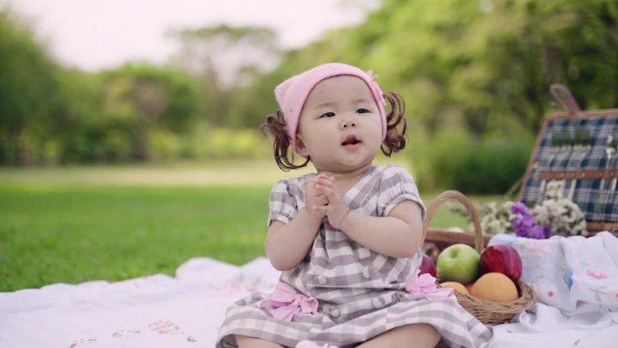 快乐可爱的小女孩坐在公园里，欢快地拿着鲜花。
