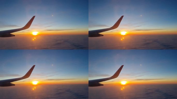 在夕阳和云彩的映衬下飞行的飞机机翼