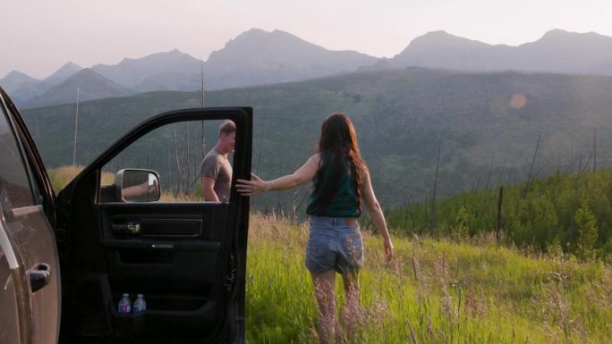 年轻夫妇在靠近车门的山坡上欣赏风景