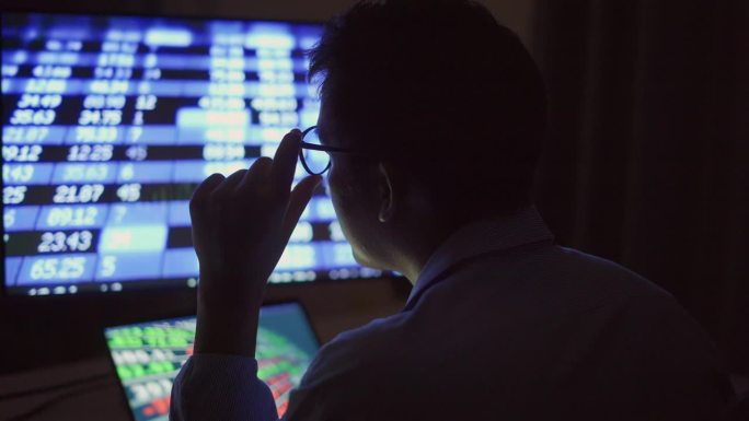 一个商人晚上在电脑前分析数据，情绪紧张。