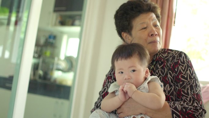 一位亚洲祖母抱着她八个月大的孙子，充满了真挚的爱