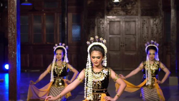 一群印度尼西亚舞者在舞台上的蓝色灯光下一起跳舞