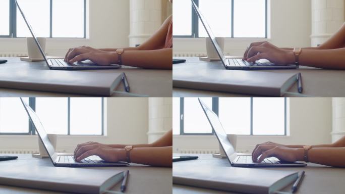 一个匿名的黑皮肤女人的手在家里用笔记本电脑打字
