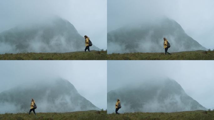 独立旅行女人在暴风雨的天气仰望天空站在山顶徒步旅行者女孩穿着黄色夹克风景风景享受假期旅行冒险自然苏格