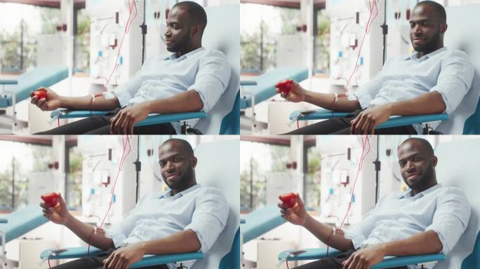 黑人商人为有需要的人献血。一名非洲男子挤压心形红球，将血液通过管道泵入袋子，并在镜头前展示，作为支持