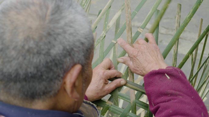 乡村老人在院子里用竹条编竹篮