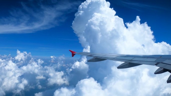 从航空公司看向前方，看到飞机的翅膀在空域上空飞行，看到许多云，蓝天，明亮，美丽的旅行概念