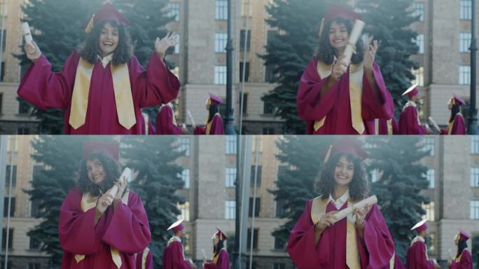 大学校园里，戴着毕业帽、穿着毕业礼服、笑着、尖叫着、挥舞着文凭的狂喜女孩的慢动作肖像