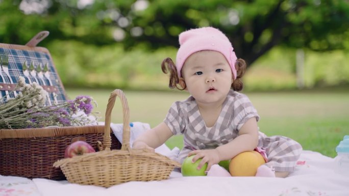 快乐可爱的小女孩坐在公园里拿着橘子和苹果享受。