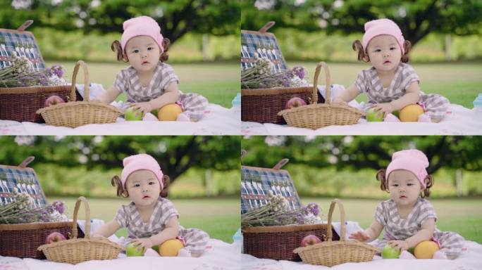 快乐可爱的小女孩坐在公园里拿着橘子和苹果享受。