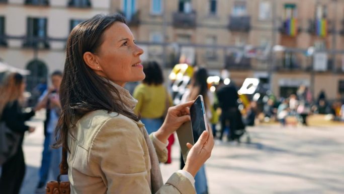 女游客用她的智能手机在城市广场中央拍摄建筑