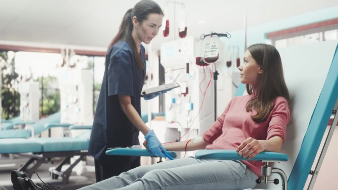 白人妇女在光明医院为有需要的人献血。女护士带着平板电脑进来检查供体的进展和健康状况。器官移植病人的捐