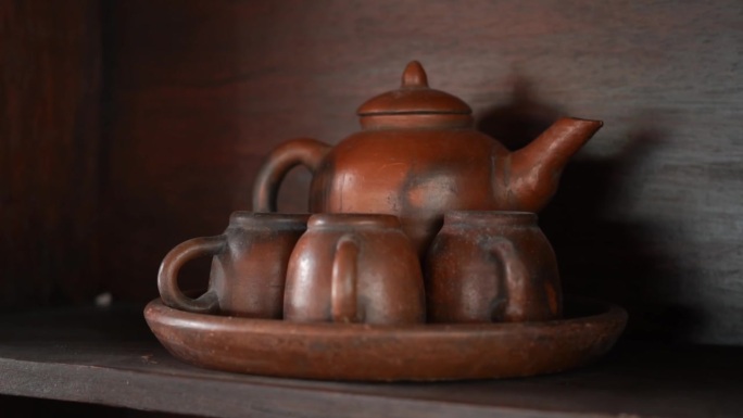 一个棕色的茶壶和杯子放在一个竹橱柜上