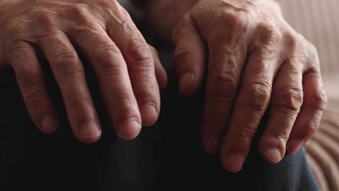 老人布满皱纹的双手放在膝盖上的特写。有选择性的重点。老年的概念，退休年龄，孤独，养老院，老年病