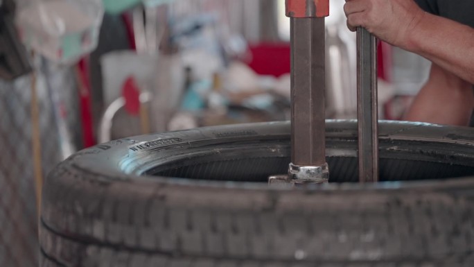 一位熟练的技工正在给合金轮毂装新的汽车轮胎。机械师在修理车库里的汽车方面有专门知识和技巧。修理工在一
