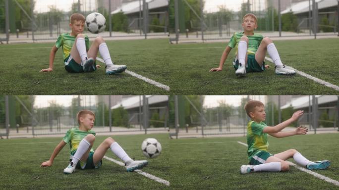 穿着足球服的男孩正在一个小型足球场练习。一个年轻的足球运动员躺着试图把球踢起来。
