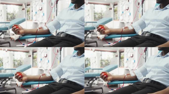 黑人男性献血者的手与连接导管的特写镜头。非洲商人挤压心形球，将血液通过管道泵入袋中。器官移植病人的捐