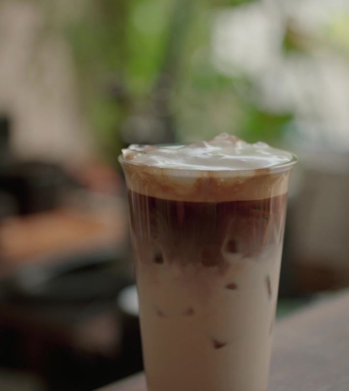 咖啡师将牛奶倒入冰咖啡中，以制作冰拿铁。