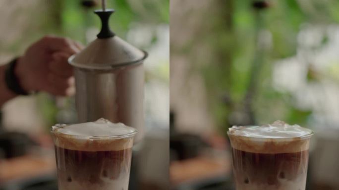咖啡师将牛奶倒入冰咖啡中，以制作冰拿铁。