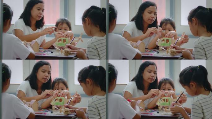 一个亚洲女孩和她的姐姐正在给一个木制玩具上色