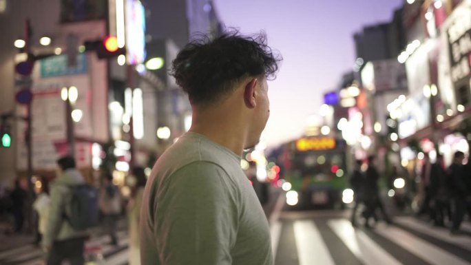 亚洲男子游客走在繁忙的十字路口，抬头看/东京，日本。