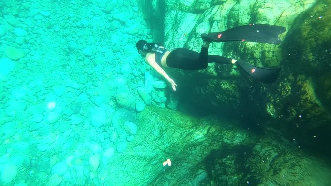 穿着长脚蹼的女生在水下快乐的自由潜水