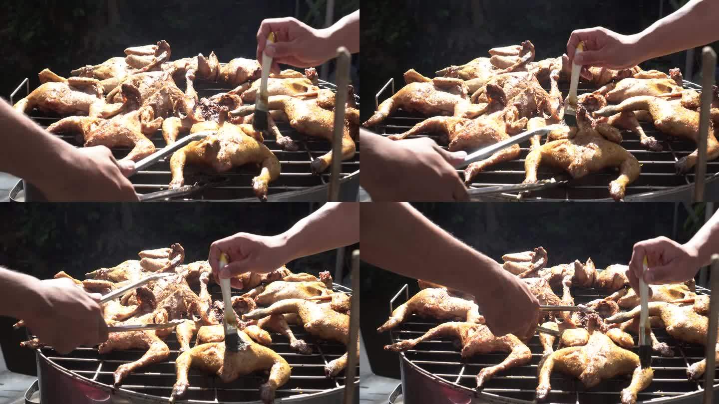 用手在木炭烧烤架上旋转烤整只腌好的鸡，加入酱汁和香草