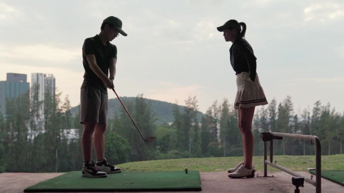 活跃的女高尔夫球手在高尔夫球场教一个男孩如何打高尔夫球
