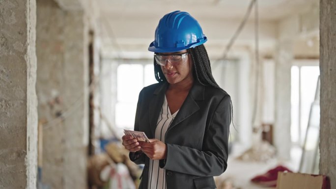 非裔美国女建筑师微笑着自信地在建筑工地数钱