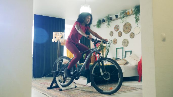 运动在家，健身在家的理念。一个非洲女人在封锁期间骑自行车练习