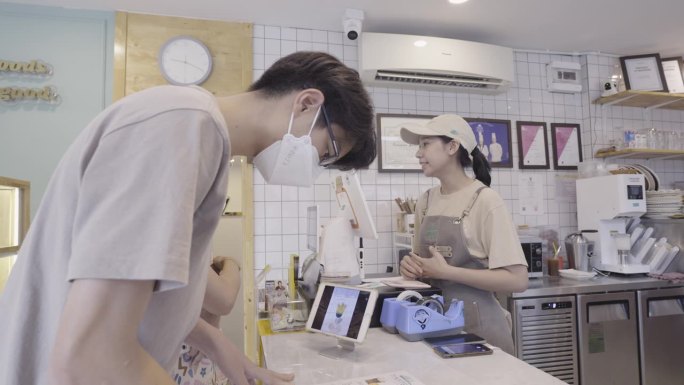 年轻人在咖啡店用手机支付外卖咖啡。