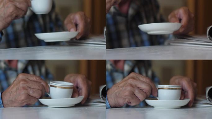 老人的手坐在桌子旁，用杯子喝茶，旁边是一叠报纸，老人的生活方式，一个老人在家里喝咖啡