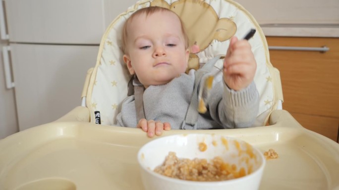 小男孩自己喝粥时弄得一团糟的画像。育儿理念，健康营养和婴儿喂养