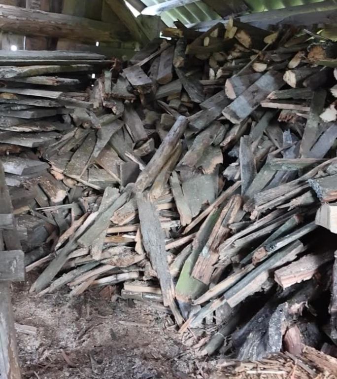 在旧谷仓里砍柴。叠得整整齐齐。你可以看到一个劈柴的装置。垂直视频。